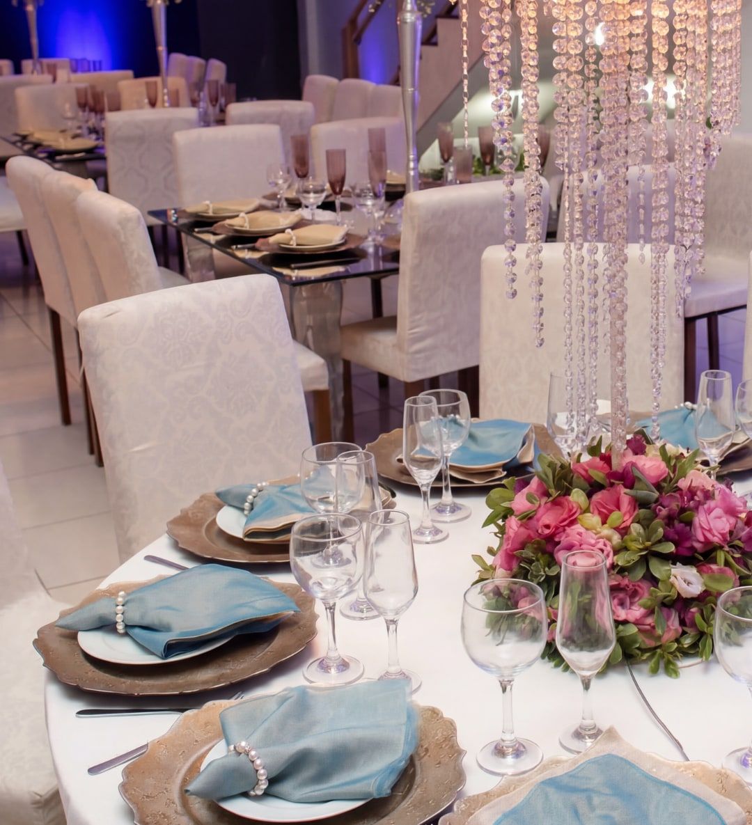 Mesas de casamento com guardanapos azuis e arranjos de flores