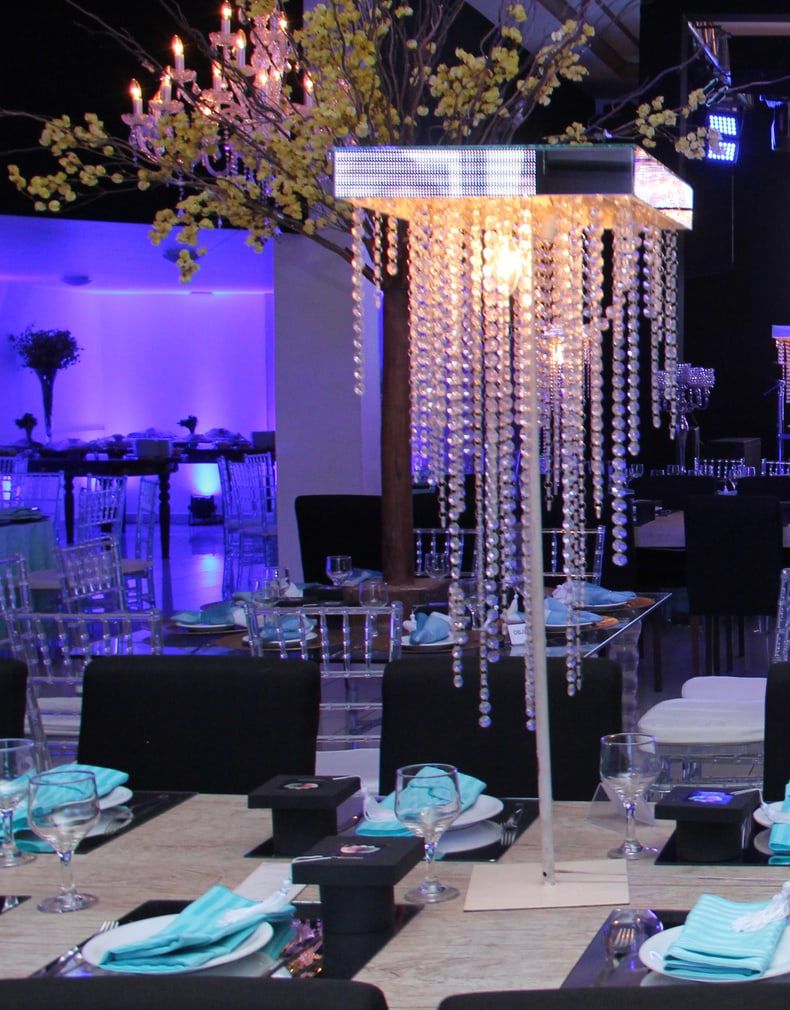 Árvore de flores amarelas e luminária de cristais sobre as mesas do baile de formatura